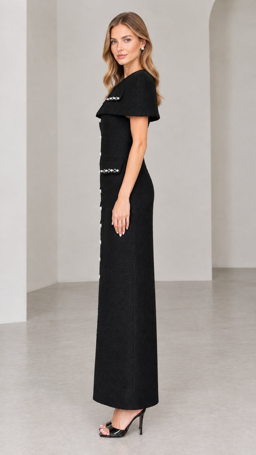 Side profile view of black structured capelet tweed column maxi dress