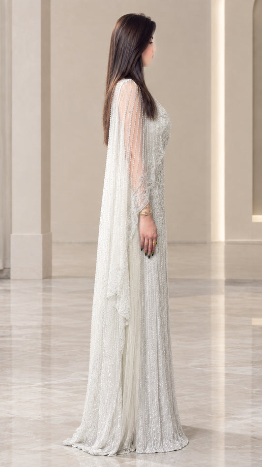 Side profile of woman wearing silver floor-length cape evening dress