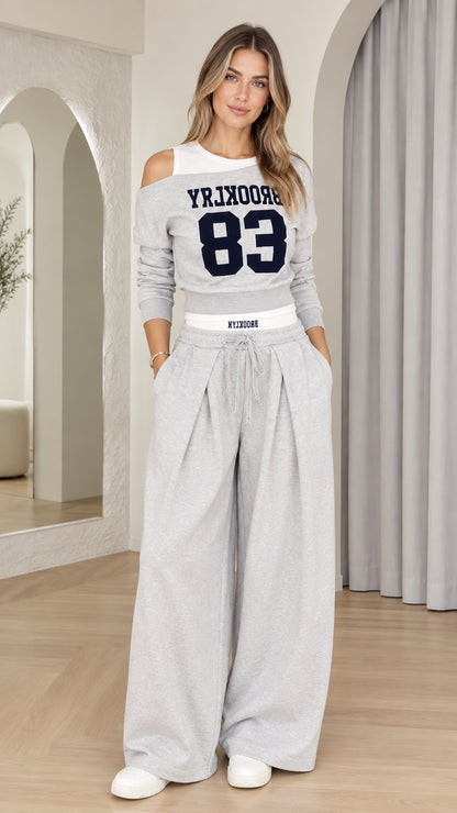 Front full view of woman wearing Heather Grey Brooklyn 83 cutout sweatshirt and pleated wide-leg pants set