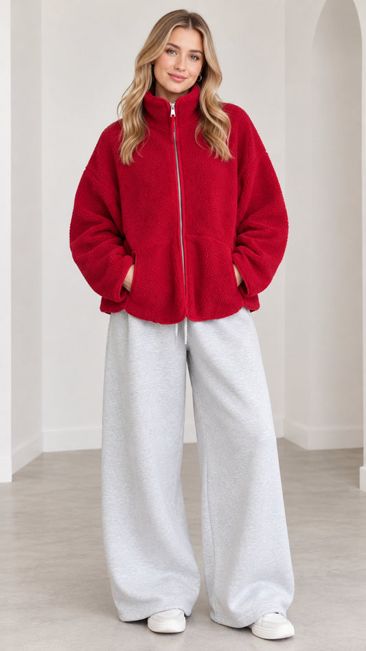 Front view of model wearing red sherpa fleece zip-up jacket with grey sweatpants