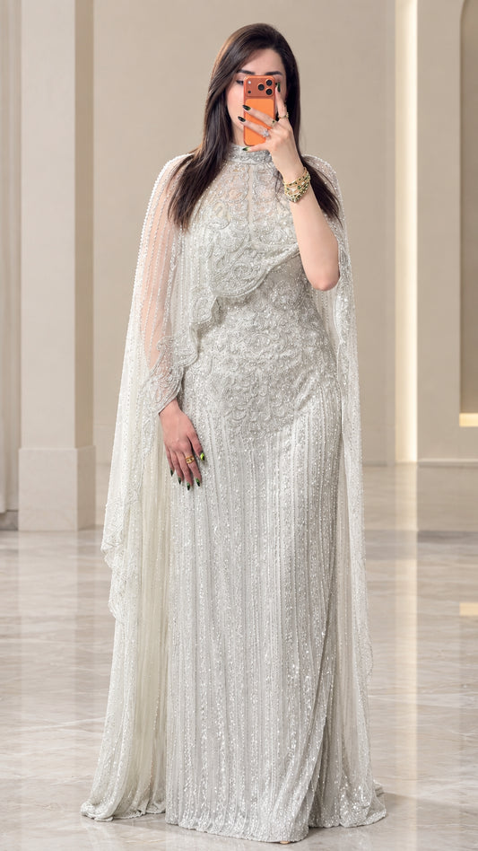 Front view of woman wearing silver beaded cape evening gown with high neckline
