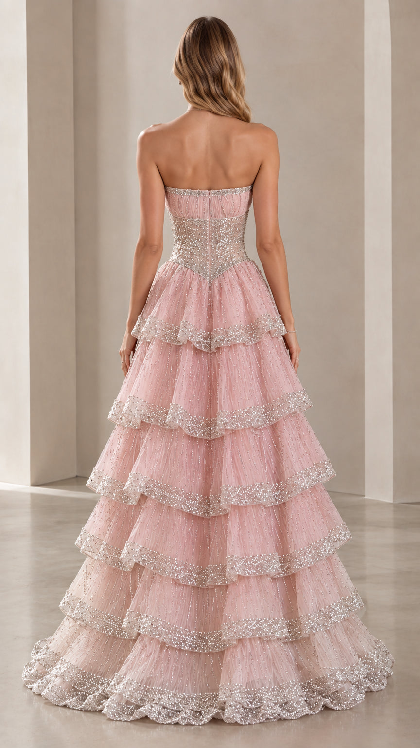 Back view of model in Blush Pink strapless tiered evening gown