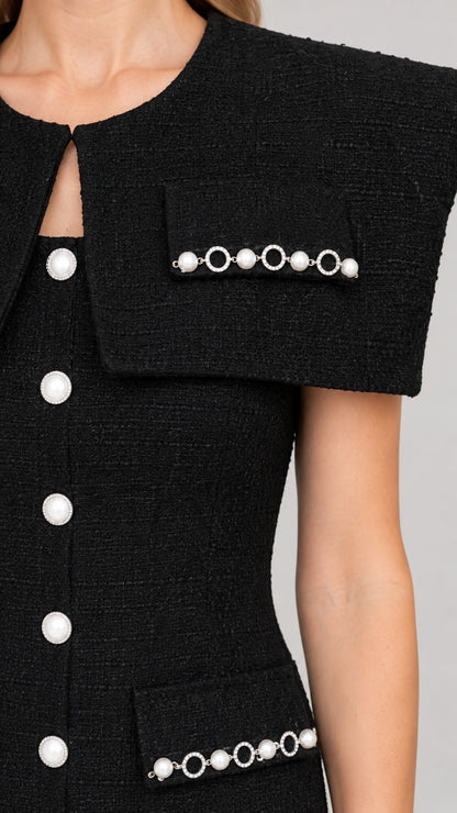 Close-up detail of black tweed capelet neckline and pearl-embellished pockets