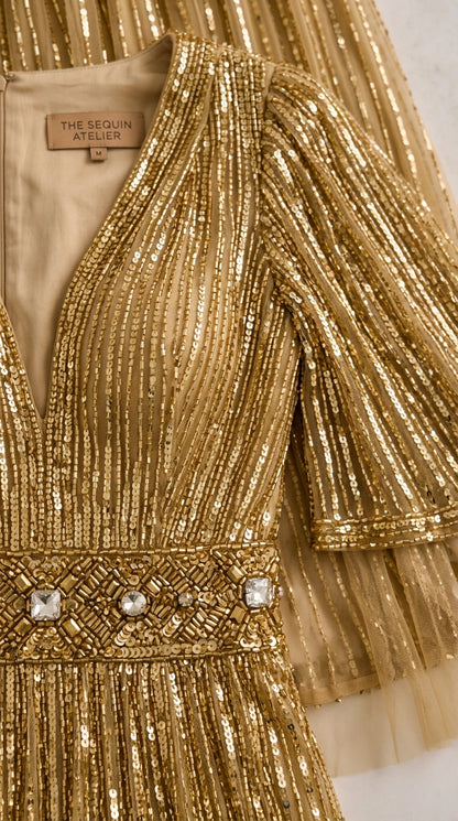 Close-up detail of V-neckline and embellished waistband on gold sequin gown