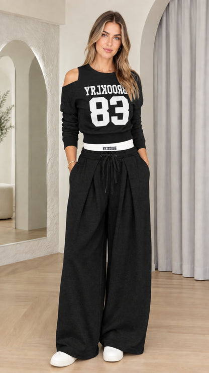 Front view of woman wearing Black Brooklyn 83 cutout sweatshirt and wide-leg sweatpants set